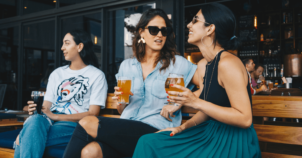 women sitting outside a bar having a beer